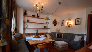 Una sala de estar acogedora con una mesa de comedor de madera, un sofá azul estampado y una araña.