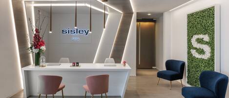 A reception area with a white counter, two pink chairs, and two blue chairs.