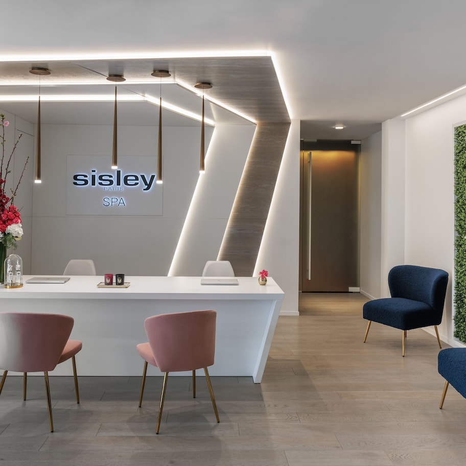 A reception area with a white counter, two pink chairs, and two blue chairs.