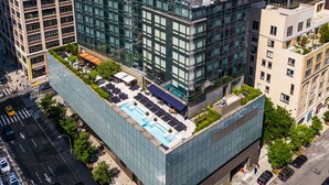 Un immeuble moderne de grande hauteur, doté d’une piscine et d’un espace de détente sur le toit, et entouré d’autres bâtiments.