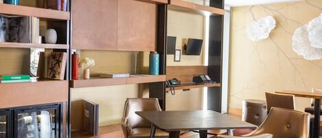 Un moderno vestíbulo de hotel con mostrador de recepción de madera, asientos de cuero y una pared decorativa con arte abstracto.