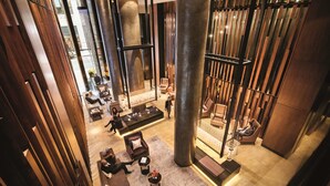 Un hall d’entrée spacieux, doté de hauts plafonds, de grands panneaux en bois et d’un espace de détente central avec des canapés et une table basse.