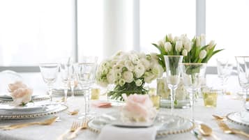 A table set for a formal event with white tablecloths, clear glassware, and a centerpiece of white flowers.