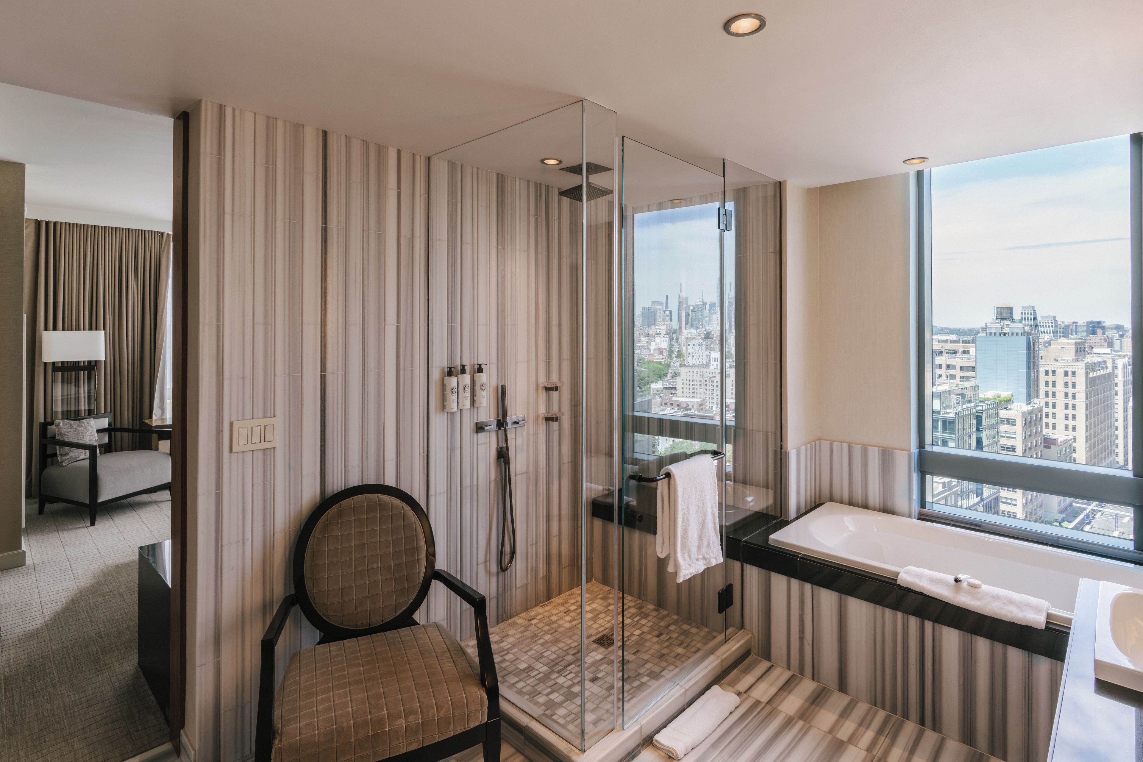 Een moderne badkamer met een douchecabine van glas, een bad en uitzicht over de stad.