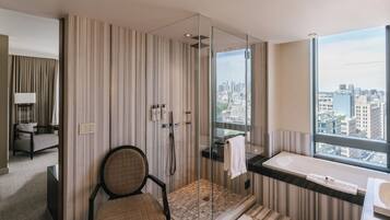 Een moderne badkamer met een douchecabine van glas, een bad en uitzicht over de stad.