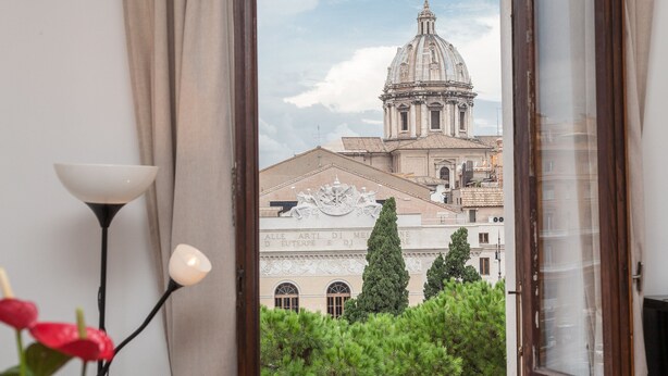 A view through a window of a building with a dome and classical architecture, including a statue and inscriptions. - Ancient Rome View Apartment (Rome)