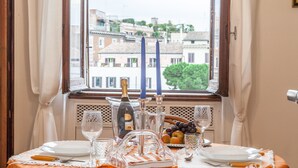 A table set for a meal with a bottle of champagne, glasses, and a fruit bowl. - Ancient Rome View Apartment (Rome)