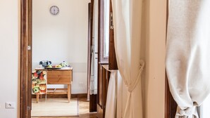A hallway with a wooden table displaying fruits and a clock on the wall. - Ancient Rome View Apartment (Rome)