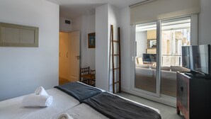A hotel room with a bed, a TV, a sliding glass door to a balcony, and a wooden chair. - Espigon Central - Punta del Moral Beach PEHC14P79 (Punta del Moral)