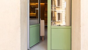 A narrow hallway with a green door leading to a bathroom with a mirror and sink. - Studio with terrace in Born (Barcelona)