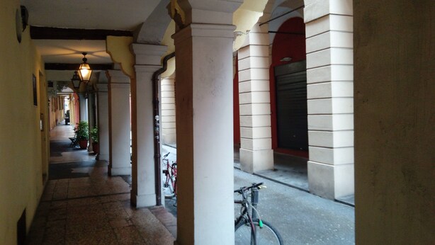 A corridor with arches, columns, and a bicycle. - Spacious and Beautiful 60 sqm Apartment in the Very Heart of Bologna (Bologna)