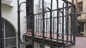 A wrought iron gate with a curved design, leading to a building with a white facade and a window with a metal grille. - Spacious and Beautiful 60 sqm Apartment in the Very Heart of Bologna (Bologna)
