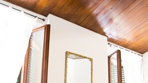 A room with a wooden ceiling, a fireplace with a stone surround, and large windows with shutters. - Spacious and Beautiful 60 sqm Apartment in the Very Heart of Bologna (Bologna)