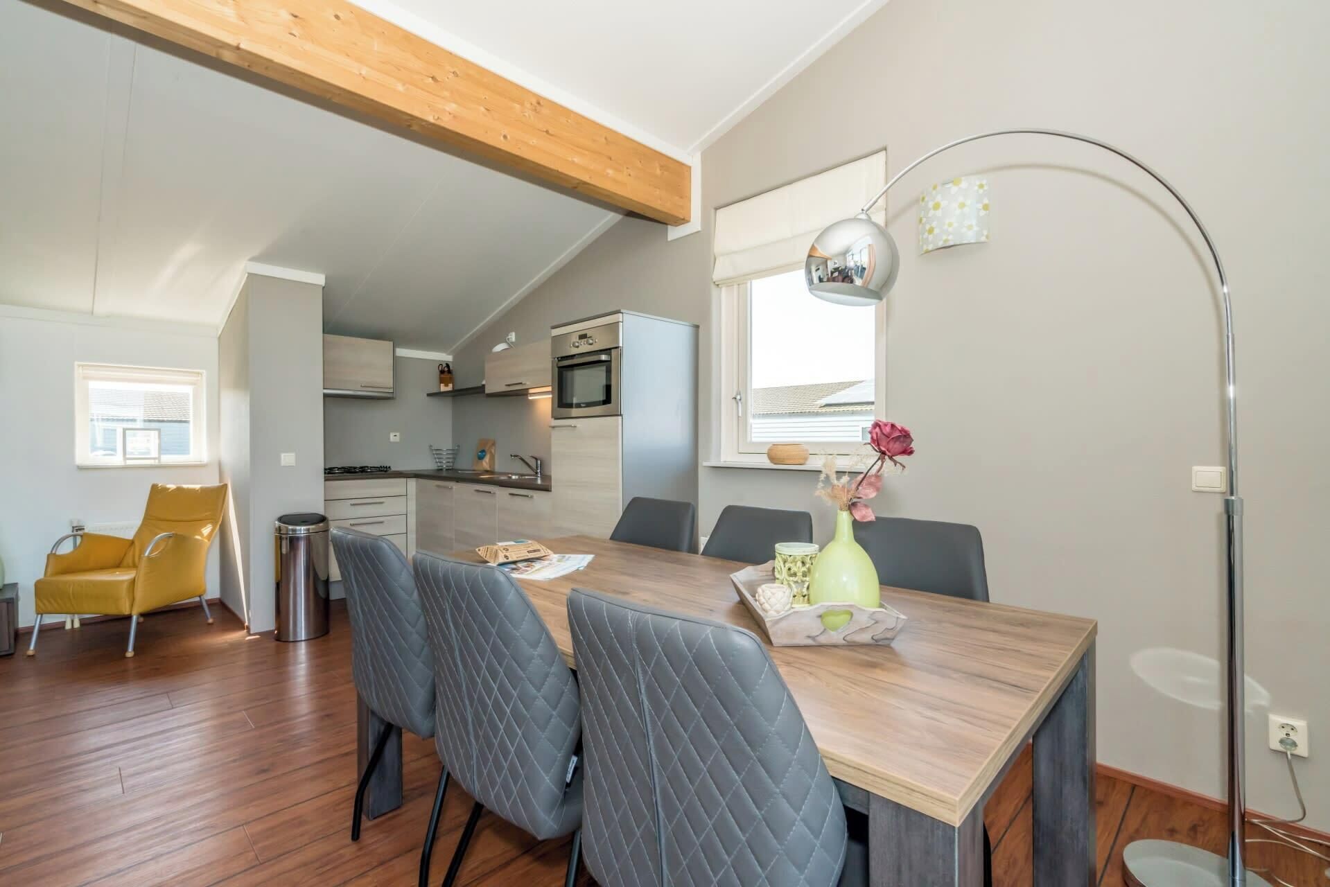 Una cocina compacta con electrodomésticos modernos, una zona de comedor con una mesa y sillas de madera, y un ventanal con vistas.