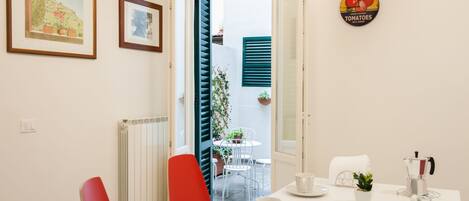 Un comedor con una mesa preparada para dos, un radiador y vistas al exterior.