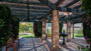 A covered outdoor area with a brick floor, benches, and a water feature. - Prado Golf - Isla Canela Golf GPHG45P86 (Isla Canela)