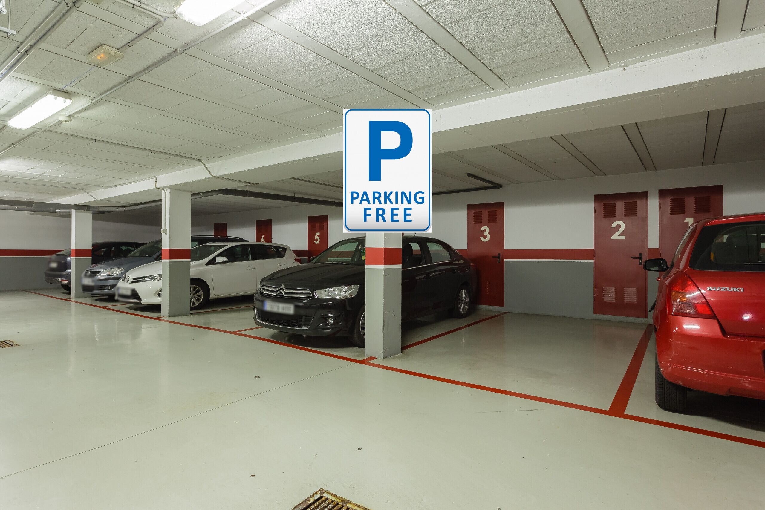 Garagem de estacionamento com um aviso 'PARKING FREE', vagas numeradas e carros estacionados no interior.