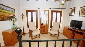 A living room with two armchairs, a wooden cabinet, a television, and a painting on the wall.