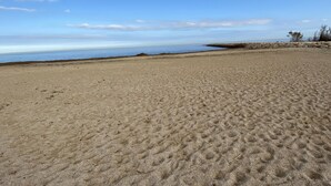 Ampia spiaggia sabbiosa con cielo sereno e mare calmo.
