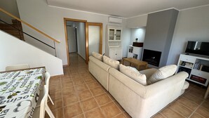 Una sala de estar con sofá, televisión y un comedor con mesa.