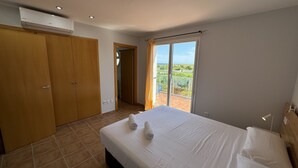 Un dormitorio con cama, armario, balcón con vistas y aire acondicionado.