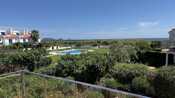 Zona residencial con piscina, exuberante vegetación y vistas al mar.