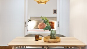 A dining area with a wooden table, chairs, a candle, and a vase with green foliage. - Columbus Apartment, - One Bedroom Apartment, Sleeps 2 (Barcelona)