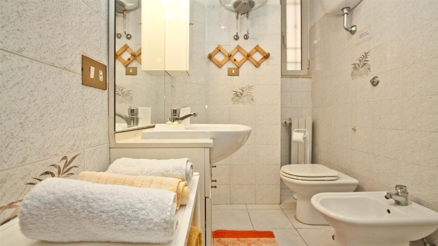 Un baño con lavamanos, inodoro, bidé y toallas.