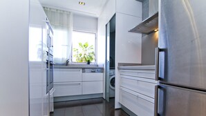 A modern kitchen with stainless steel appliances, white cabinetry, and a built-in washing machine. - SOLUXE Apartment - Only Families - Beachfront (Salou)