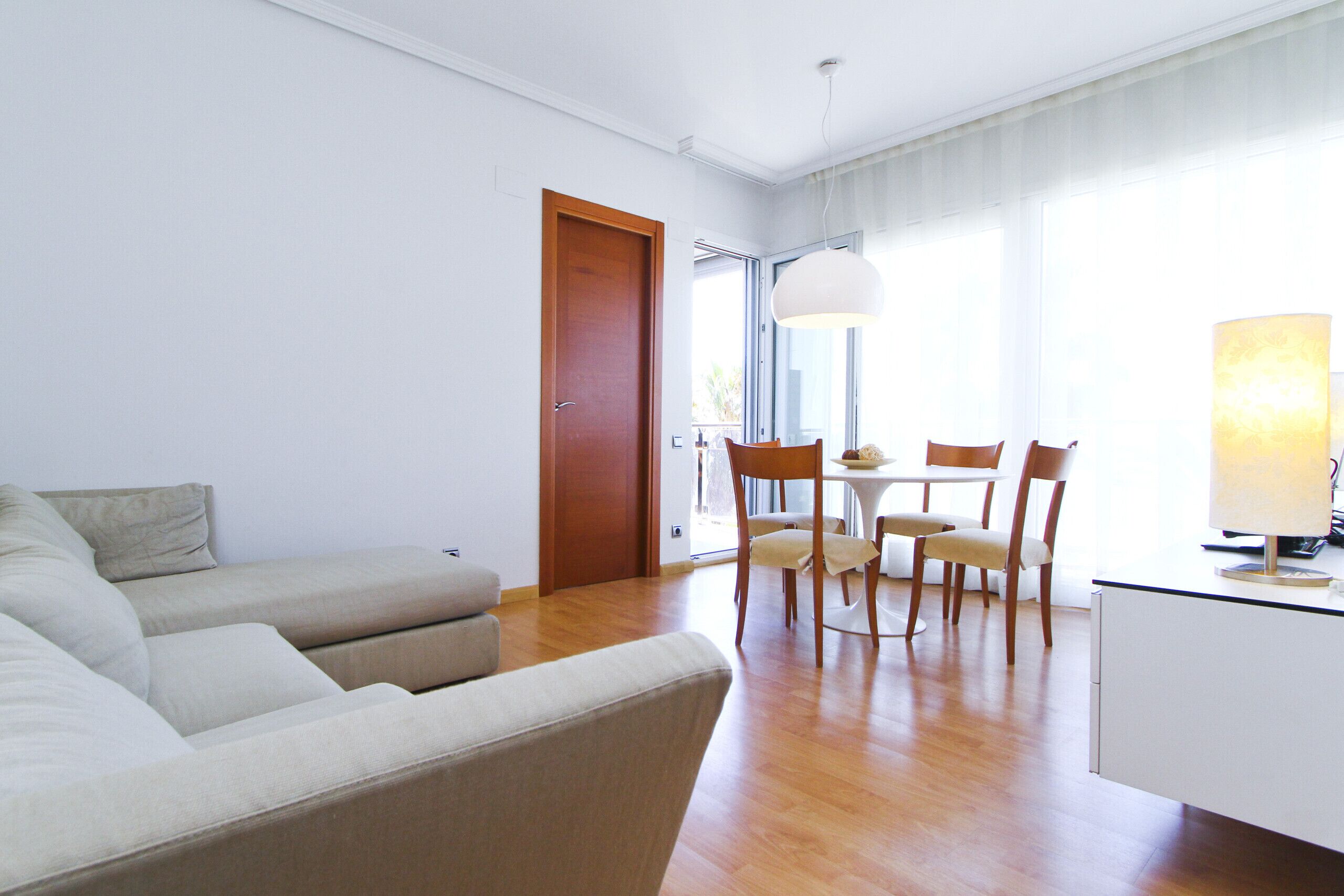 Uma sala de estar moderna com um sofá, uma mesa de jantar com cadeiras e um abajur.