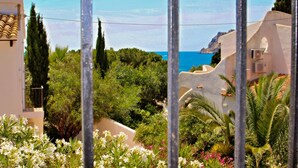 Un paysage côtier offrant une vue sur la mer, bordé d’une végétation luxuriante et ponctué de bâtiments blancs aux toits de tuiles rouges.