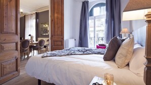 Ein Hotelzimmer mit einem großen Bett, einem Holzschrank, einem Schreibtisch mit Stuhl und Blick auf die Stadt durch das Fenster.