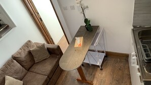 A compact living space with a brown sofa, a small wooden table, and a white radiator.