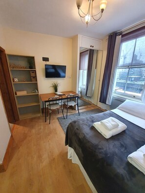 Een hotelkamer met een bed, een bureau met stoelen, een televisietoestel en een raam met gordijnen.