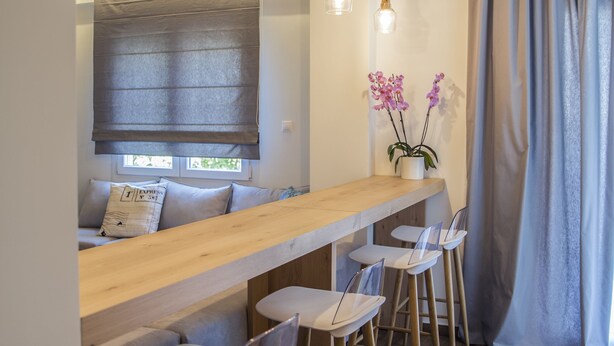 Une cuisine moderne avec un plan de travail en bois, des tabourets de bar, des luminaires suspendus et une fenêtre offrant une belle vue.