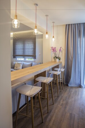 Moderni keittiö, jossa on puinen työtaso, baarituolit, riippuvalaisimet ja ikkuna, josta on kaunis näkymä.