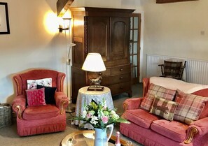 Relax in this inviting living room with a traditional armchair, sofa, and wooden wardrobe.