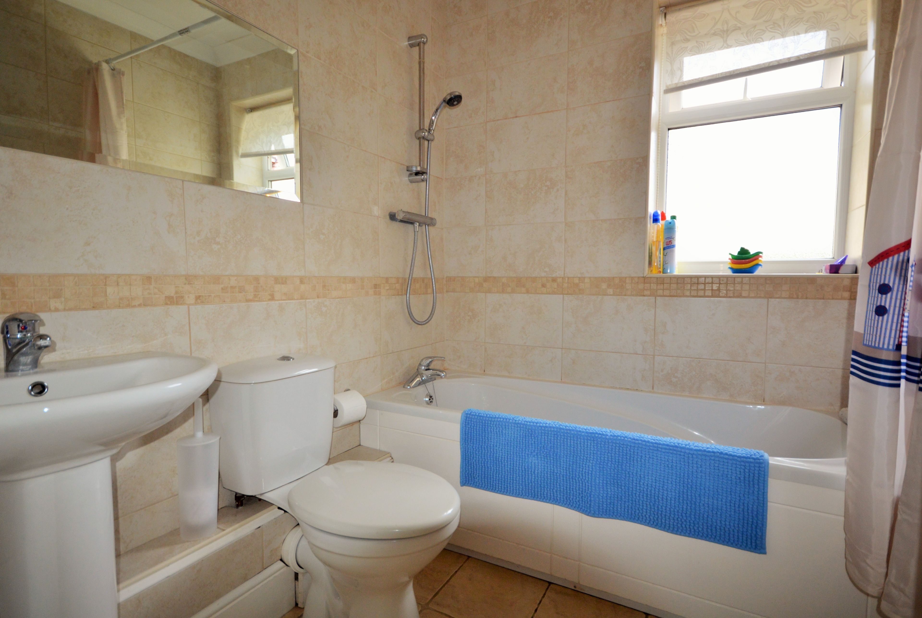 A bathroom with a sink, toilet, bathtub, and a window.
