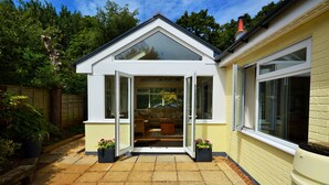A modern house with a glass door leading to a cozy interior, a brick pathway, and a fenced garden.
