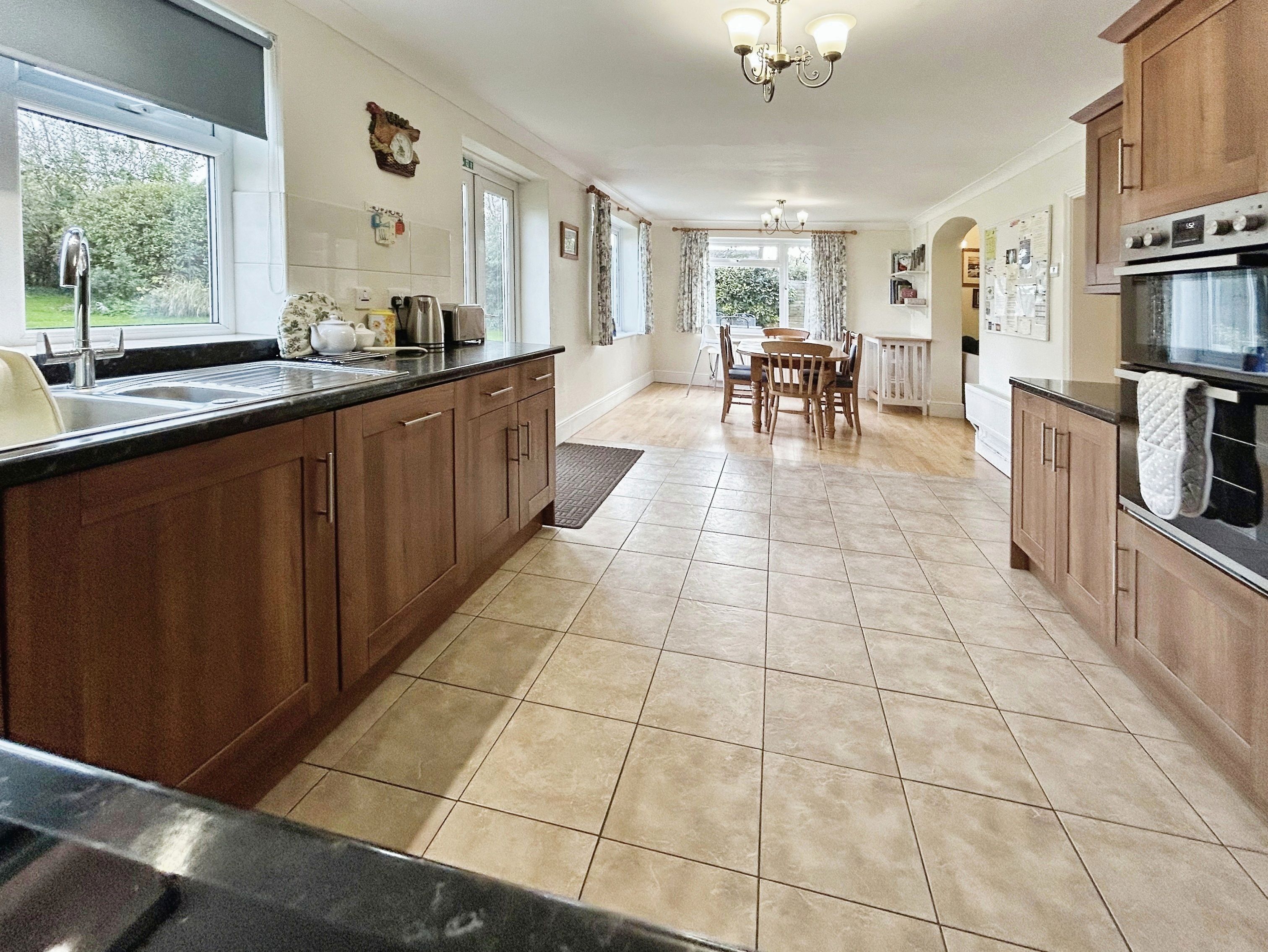 A spacious kitchen with wooden cabinets, a large island, and a dining area with a table and chairs.