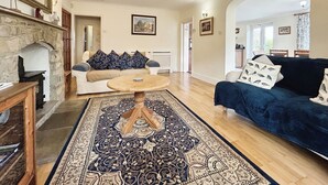 A spacious living room with a fireplace, a large rug, a sofa, and a coffee table.