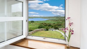 Ein Zimmer mit großem Fenster mit Blick auf eine grüne Landschaft und ein Gewässer.