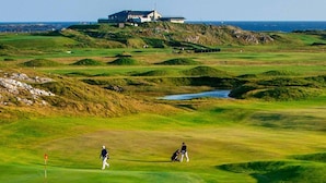 Ein Golfplatz mit Clubhaus und Meerblick.
