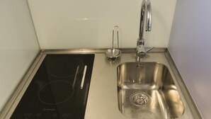 A stainless steel kitchen with a built-in induction cooktop and a sink. - The Brewmaster's House 2 | Studio Deluxe (Porto)