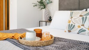 A neatly made bed with a gray knitted blanket, a woven tray with candles, and a yellow cloth. - Private villa with unique panoramic sea views, pool, bbq, 3km to the beach! (Prines)