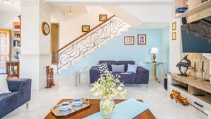 A modern living room with a staircase, a sofa, a coffee table, and a TV stand. - Private villa with unique panoramic sea views, pool, bbq, 3km to the beach! (Prines)