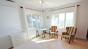 A bedroom with a bed, a desk, and two striped armchairs. - Celia - oceanfront villa in Costa Blanca (Benissa)