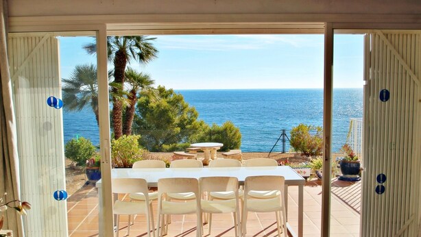 A terrace with a table and chairs, overlooking a scenic view of the sea and palm trees. - Celia - oceanfront villa in Costa Blanca (Benissa)