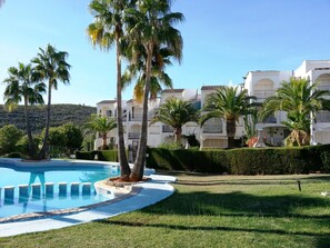 Relax by the resort's large pool surrounded by lush greenery and palm trees.