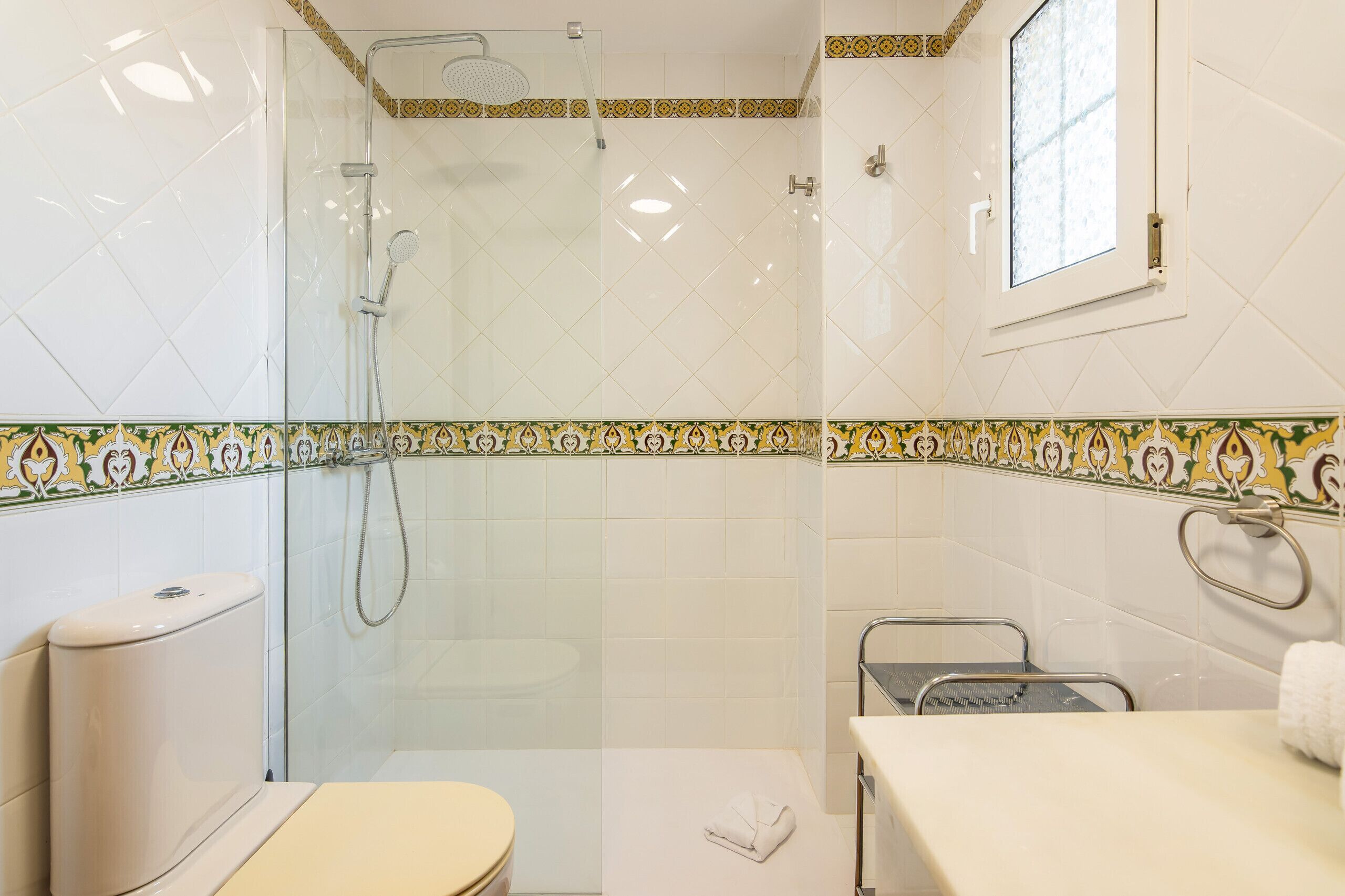 A bathroom with a glass-enclosed shower, a toilet, and a sink with a towel rack.